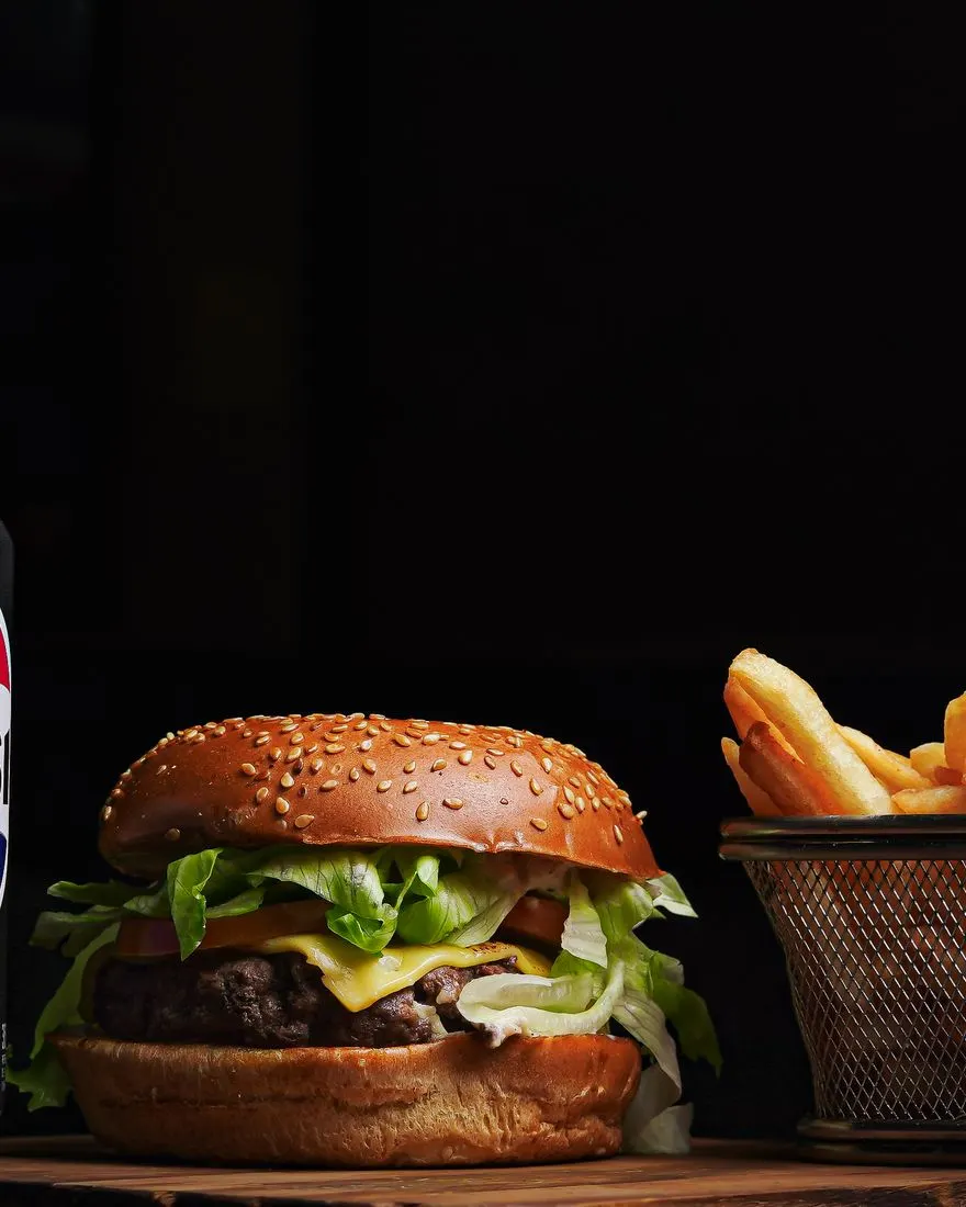 Cheeseburger with a side of fries on a dark table